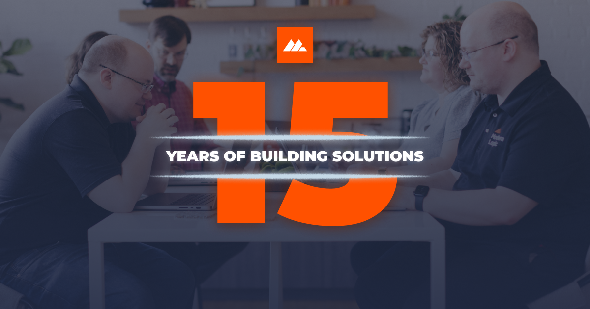 Modern Logic team gathered around a table with the number 15 in bold orange and the words “Years of Building Solutions” across the center, celebrating 15 years in business.