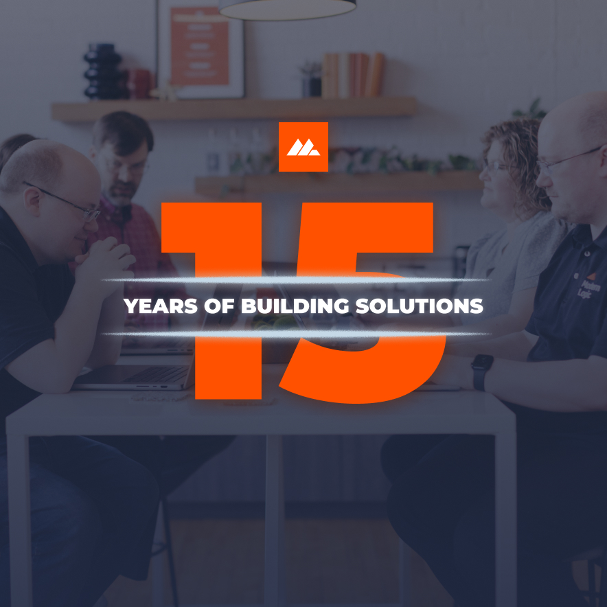 Modern Logic team gathered around a table with the number 15 in bold orange and the words “Years of Building Solutions” across the center, celebrating 15 years in business.