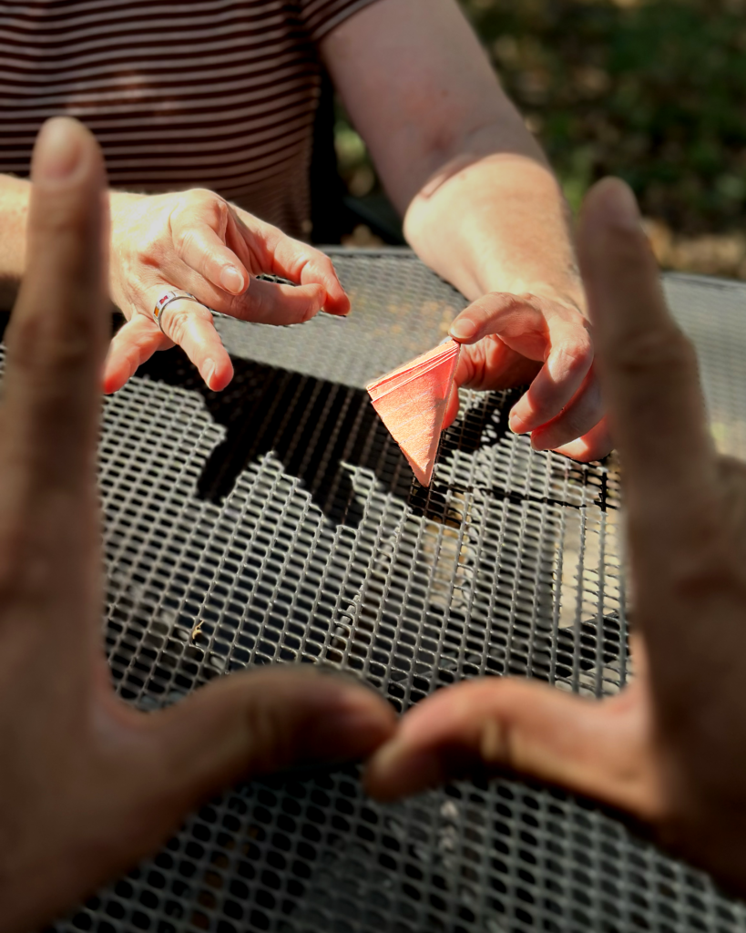 Hands flicking a paper football marked Umbraco through a pair of hands held up as goalposts